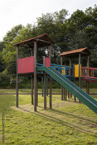 sunny day in a park surrounded by nature and wooden playground with slide, colorful entertainment place, lifestyle