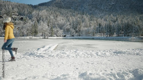 Full shot - Border Collie dog running away from his owner in front of a frozen lake surrounded by a snowy forest in daylight photo