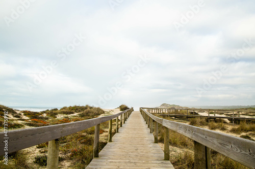 Wooden path with cloudy sky on Furadou beach in Portugal.