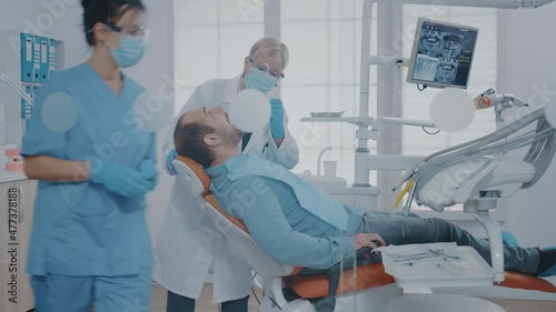 Stomatologist examining patient with mouth open in cabinet, using dental tools and equipment. Dentistry expert getting ready for surgical procedure to extract painful tooth for oral care.