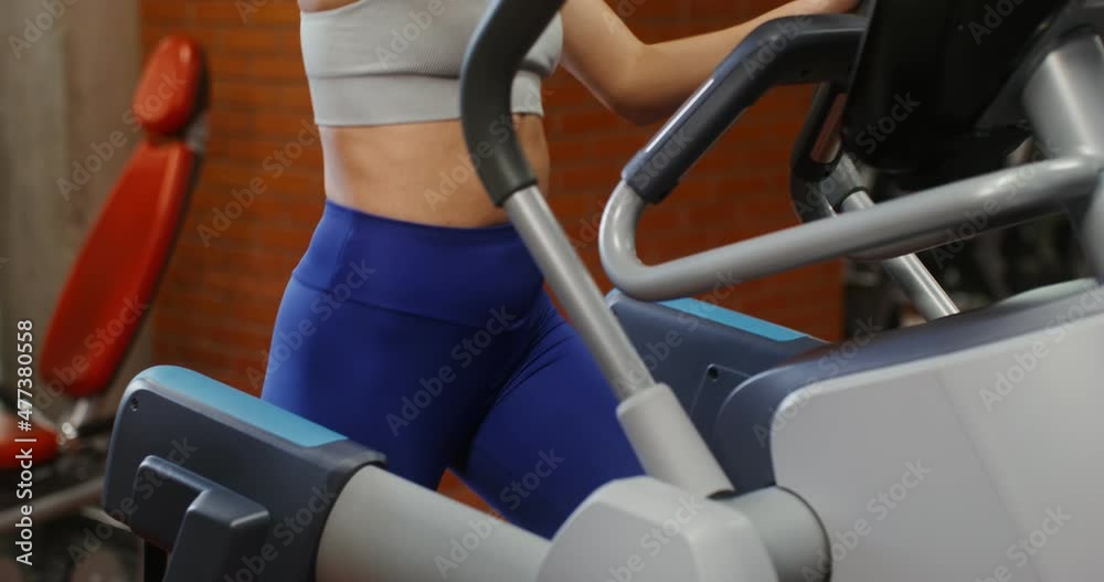 A woman is engaged in an ellipse in an indoor gym, Close-up A woman is engaged in an ellipse in an indoor gym, Close-up