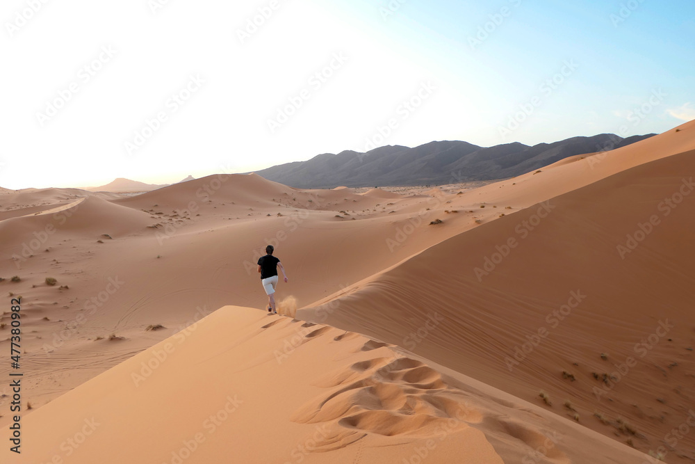 Sahara desert's dunes at sundown, Man running alone in the hot dunes enjoying a great feeling of freedom