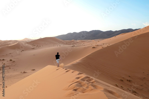 Sahara desert's dunes at sundown, Man running alone in the hot dunes enjoying a great feeling of freedom