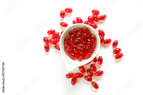 Krill oil red gelatin capsules in white ceramic cup on a white background.omega fatty acids.Healthy eating and food supplements