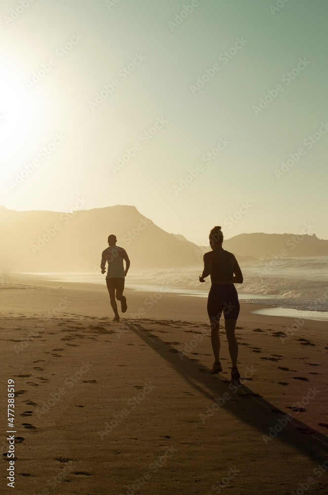 Pareja corriendo al amanecer en Playa Mermejita, Mazunte, Oaxaca