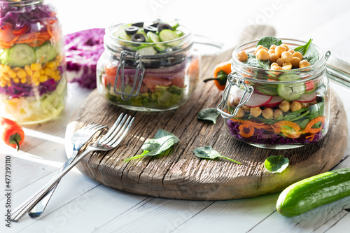 Jars of freshly made salad on a rustic wooden board.