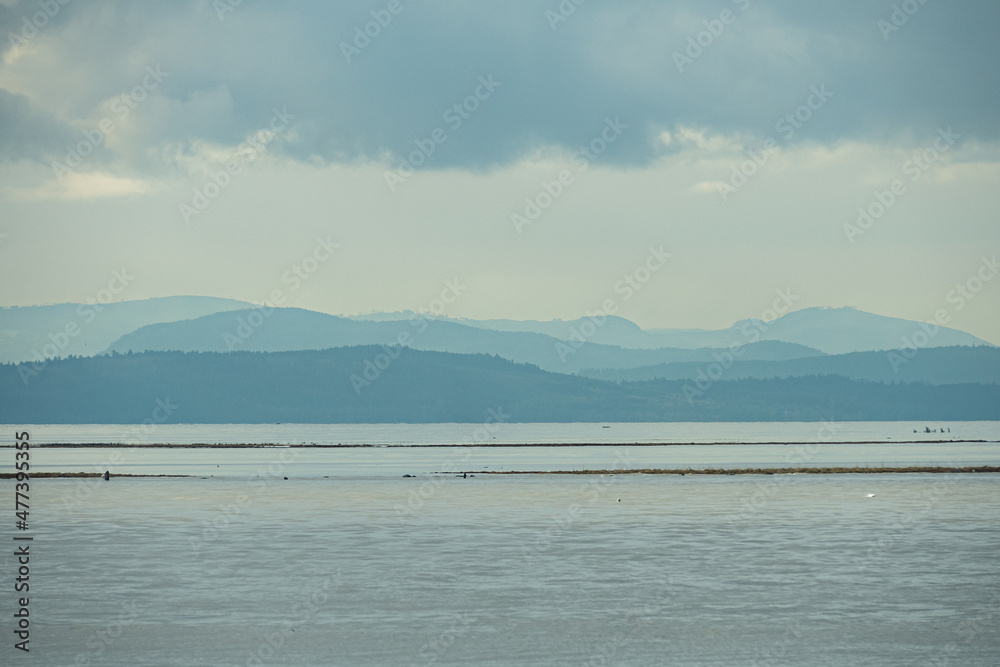 view on the coast with mountain range over the horizon under the thick cloud view on the coast with mountain range over the horizon under the thick cloud