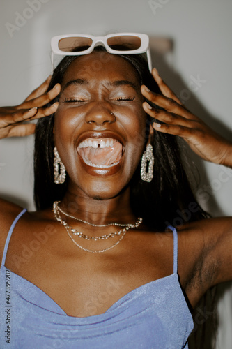 Smiling Black woman wearing gold jewelry and framed sunglasses