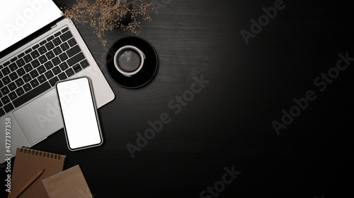 Top view modern workplace with laptop computer, smart phone ad coffee cup on black table.