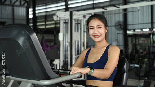 Smiling woman in sportswear exercising on bicycle in gym.