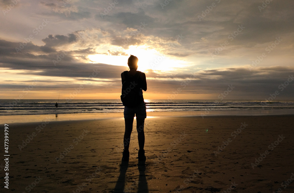 A woman enjoy the sunset at Seminyak beach in Bali Indonesia.