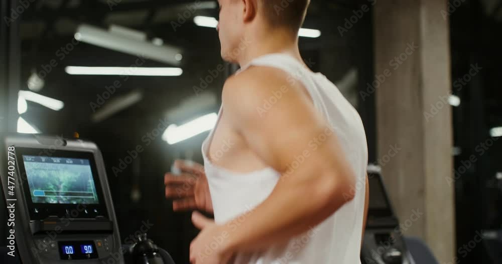 A young man of European appearance running on a treadmill in the gym