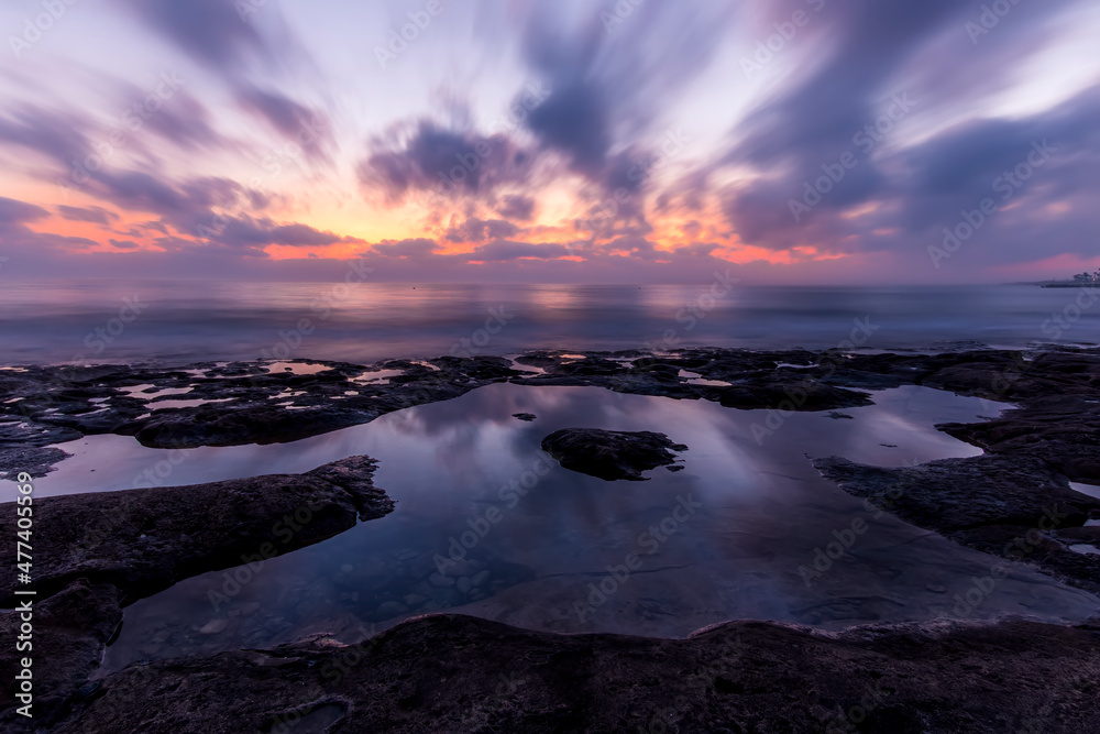 Obraz premium Twilight scenic sea landscape with beautiful shore, blurred flying dramatic blue clouds, amazing shoreline and sunset on background