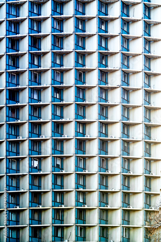 Many windows of a tall tower building with air conditioners close-up