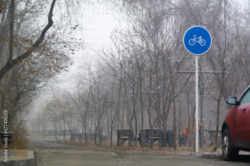 Blue round sign on a pole of bicycle lane in the autumn morning. Bike path