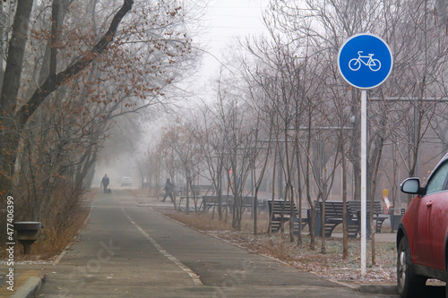 Blue round sign on a pole of bicycle lane in the autumn morning. Bike path