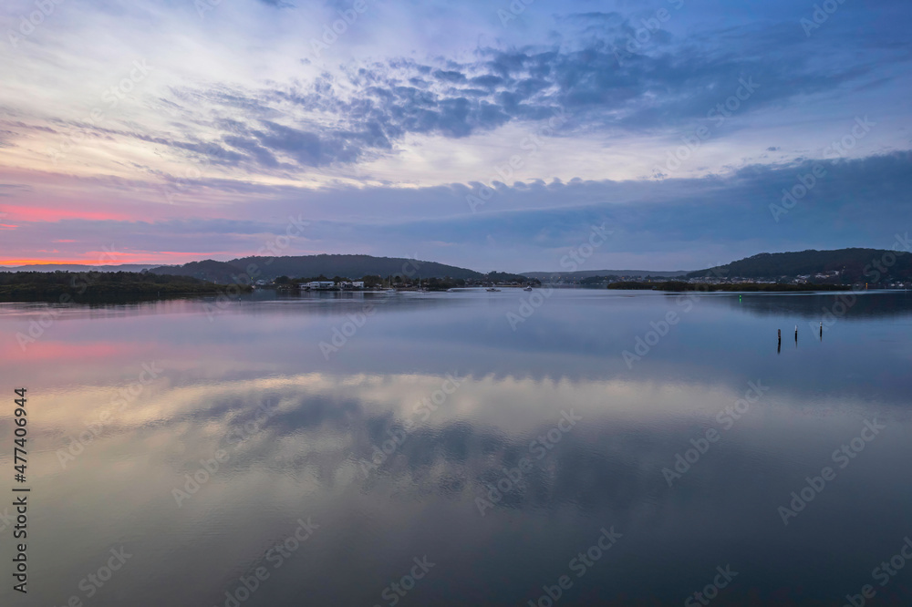 Soft and peaceful sunrise aerial waterscape with clouds and reflections