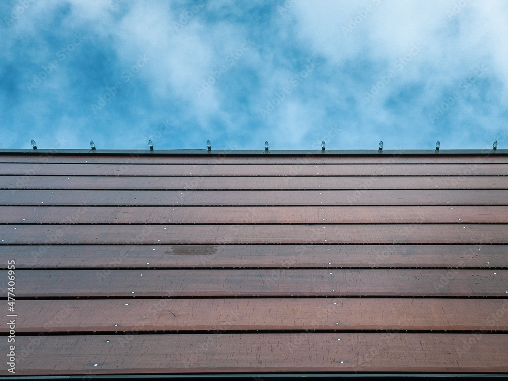 A blue cloudy sky against the lines of a wooden building facade