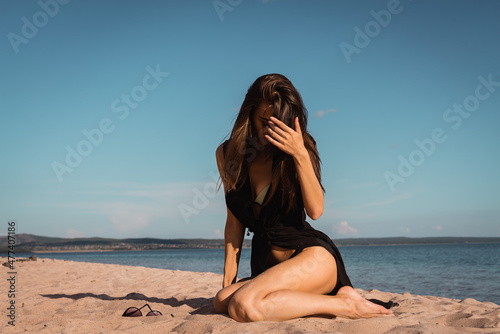 a young woman in a black dress lies on the sand. High quality photo