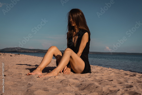 a young woman in a black dress lies on the sand. High quality photo