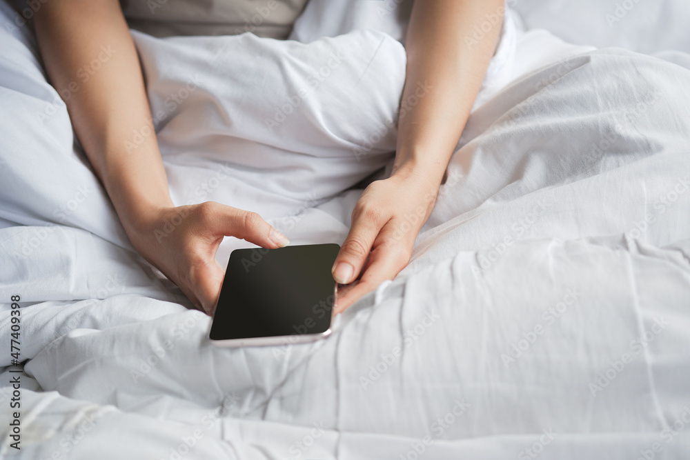 Woman's hand using phone on white bed. Clipping path. Woman's hand using phone on white bed. Clipping path.