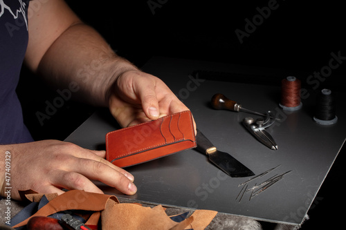 The process of making leather goods. The hands of the master work with a leather product.