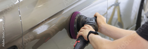 Fotografie Master repairman polishing car door using special machine in workshop closeup