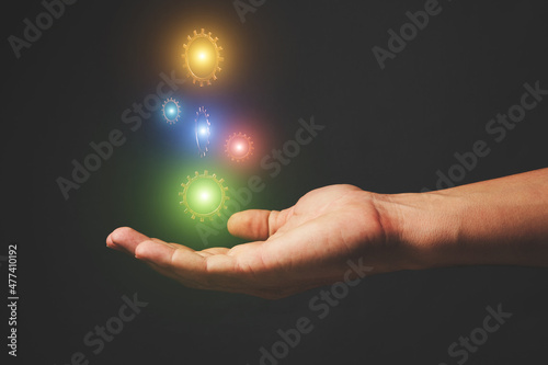 Hand holds levitating gears glowing in different colors.Concept of development, magic and technology.