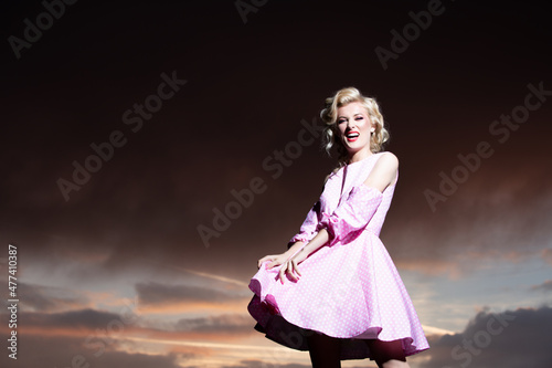 Woman in monroe dress on dramatic sky. Attractive woman in fashion outfit outside. Outdoor fashion photo of young beautiful lady enjoying spring.