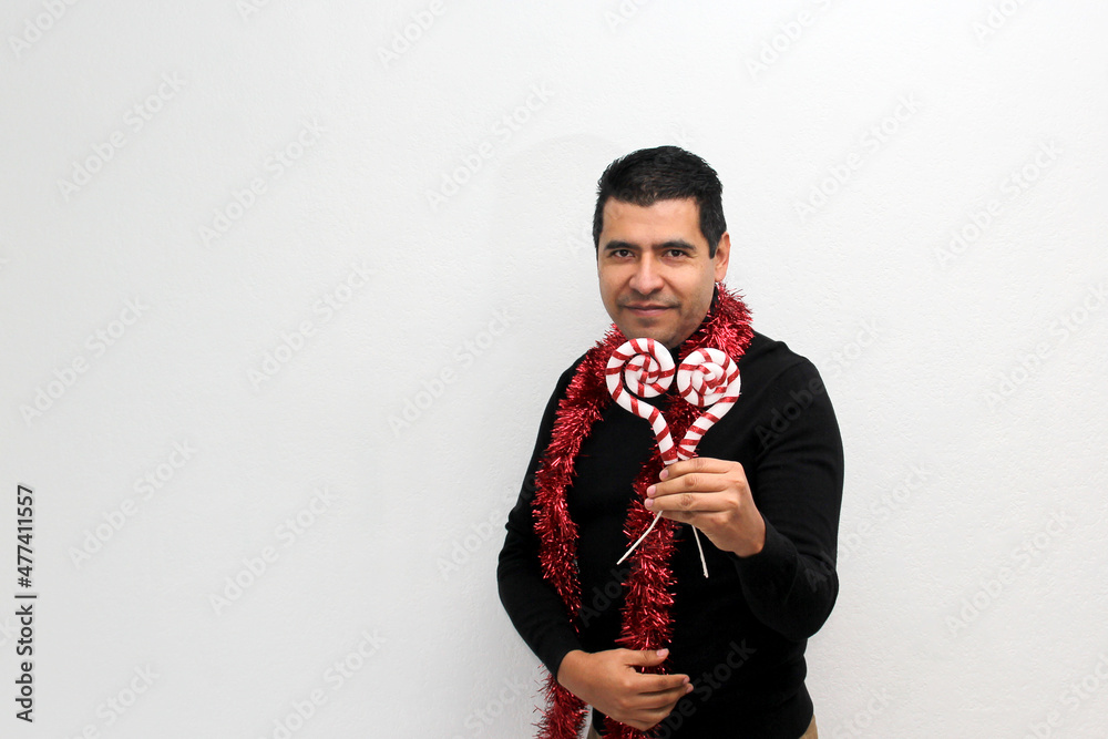 Naklejka premium Latino adult man with Christmas hat shows Christmas decorations and decorations because he is ready to celebrate the holidays and the new year 