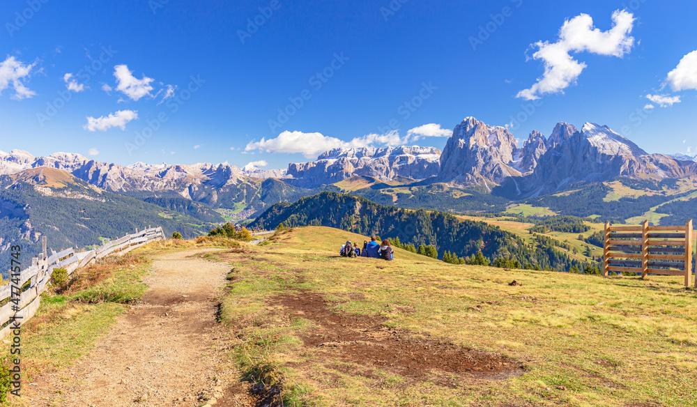 Family sitting and watching the panoramic Dolomites during a hike on Alpe Siusi