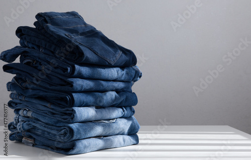 a pile of blue jeans on a light background. Close up. Copy space