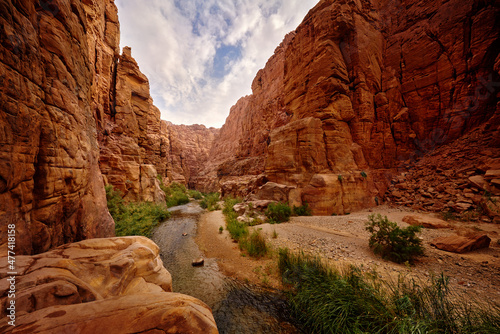Wadi Mujib Biosphere Reserve, red rock ravine gorge with river. Jordan water stream with blue sky. Wadi Mujib lowest nature reserve landscape, with a spectacular array of scenery near Dead Sea.