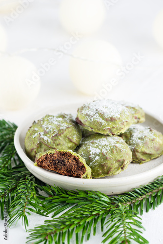 Homemade mint gingerbread cookies with matcha and chocolate and fir branches on a table. Sugar, gluten and lactose free and vegan.