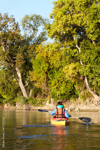Back adult woman paddling kayak on a small river near trees in rural landscape. Adventure travel leisure enjoying concept, lifestyle sport vacation