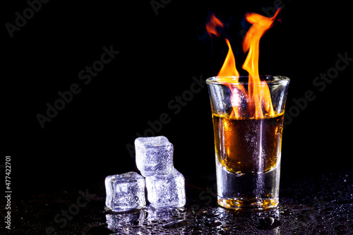 Whiskey in glass shots  with ice cubes on black background.