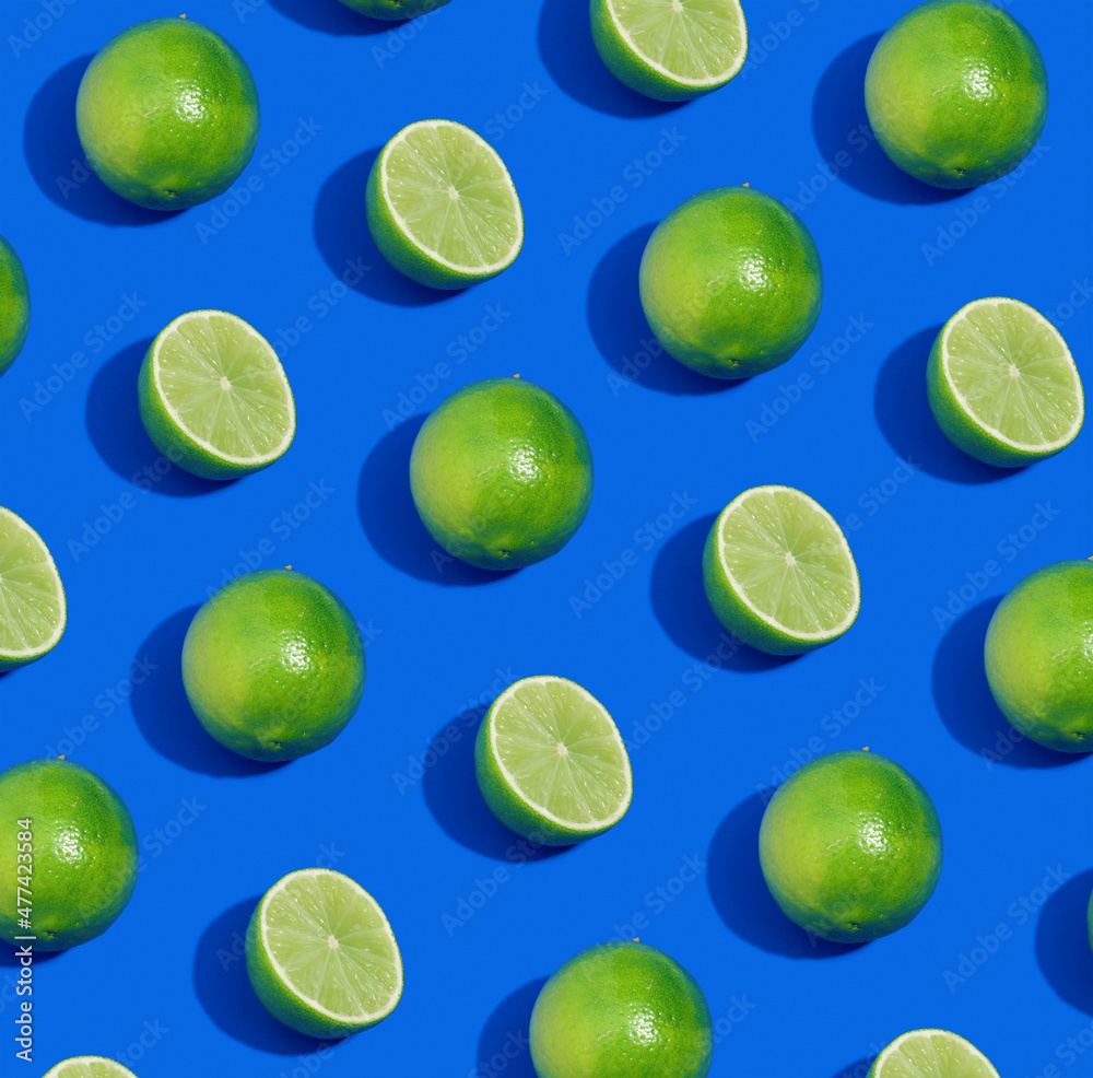 Pattern made with whole and cut limes on blue background. Bright fruit composition.