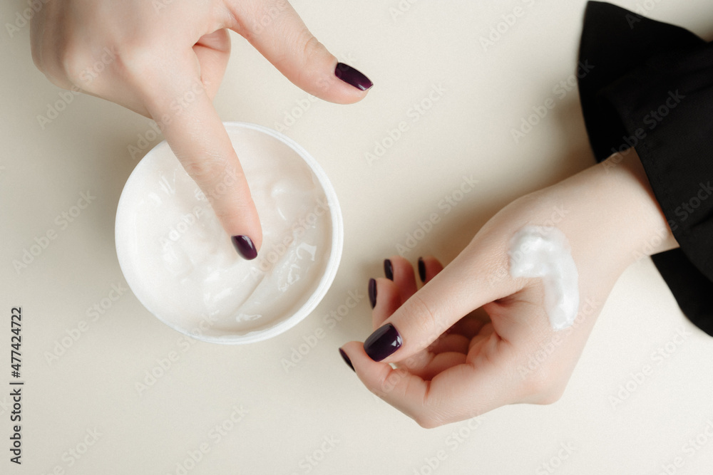 Naklejka premium Woman applying organic moisturizing hand cream. Hand skin care concept. Cold season hands skin protection. Healthcare concept. Final stage of manicure: woman uses moisturizer for the skin. 