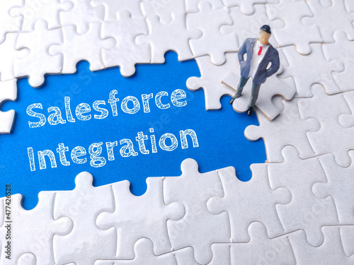 Miniature businessman on a white puzzle with text Salesforce Integration. photo