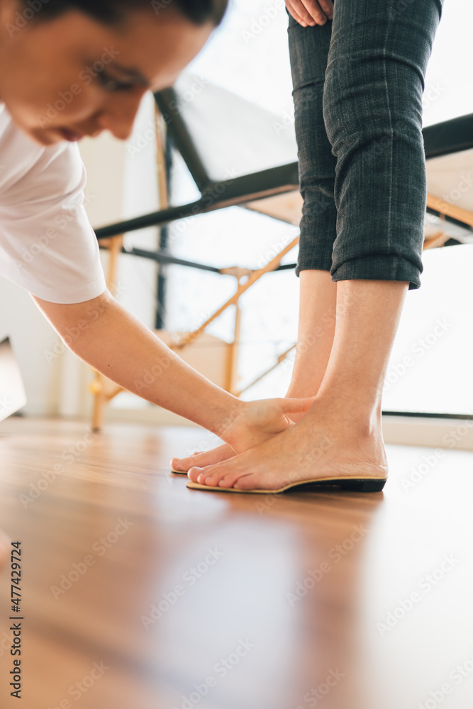 Chiropodist checking the custom foot insole of a patient on the floor in the medical center Chiropodist checking the custom foot insole of a patient on the floor in the medical center
