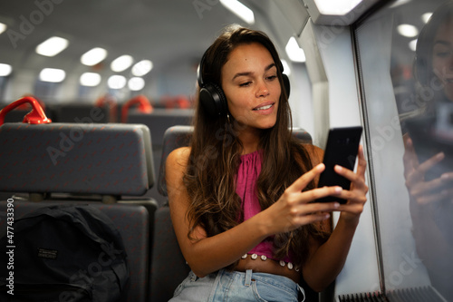  Beautiful woman travel by train. Young woman listening the music while travel by train © Jelena