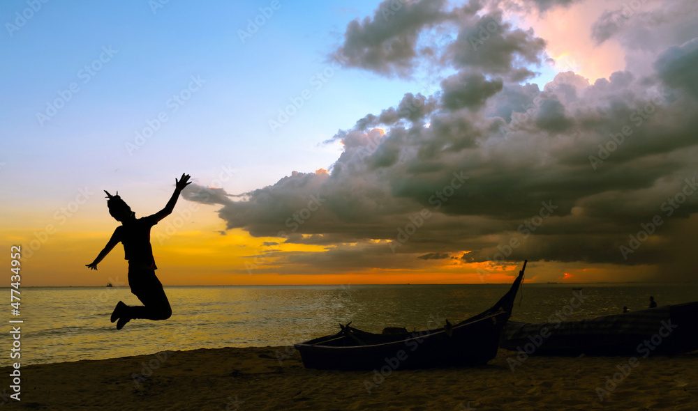 silhouette of happiness woman jumping on the beach with vintage boat at sunset time , seascape,nature.silhouette of happiness woman jumping on the beach with vintage boat at sunset time ,