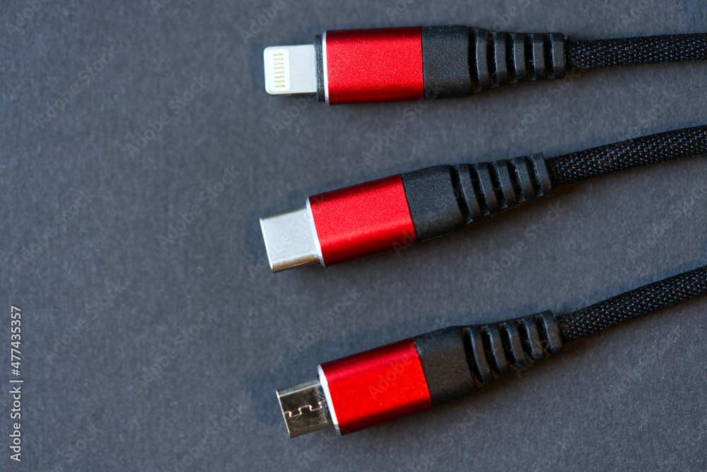 Triple red and black charging cable USB-C, USB micro and Lightning for mobile devices like mobile phones and cameras. Photo taken December 29th, 2021, Zurich, Switzerland.