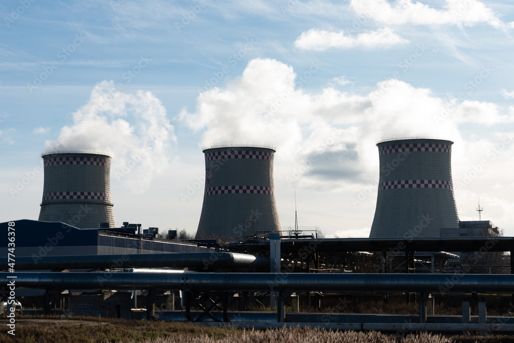 three large chimneys in a thermal power plant with smoke