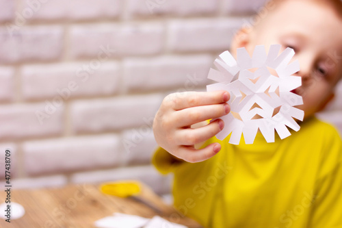 boy cuts snowflakes from paper for new year,decorations with children at home for the holiday