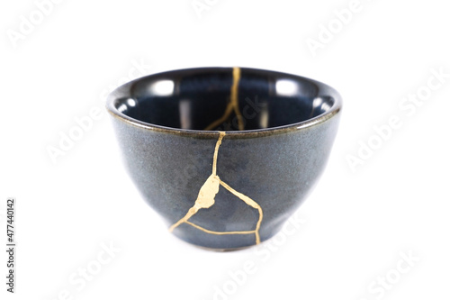 kintsugi gold cracks restoration, Japanese black bowl fixed with the antique kintsukuroi restoration technique, the beauty of imperfections, representation of a trauma