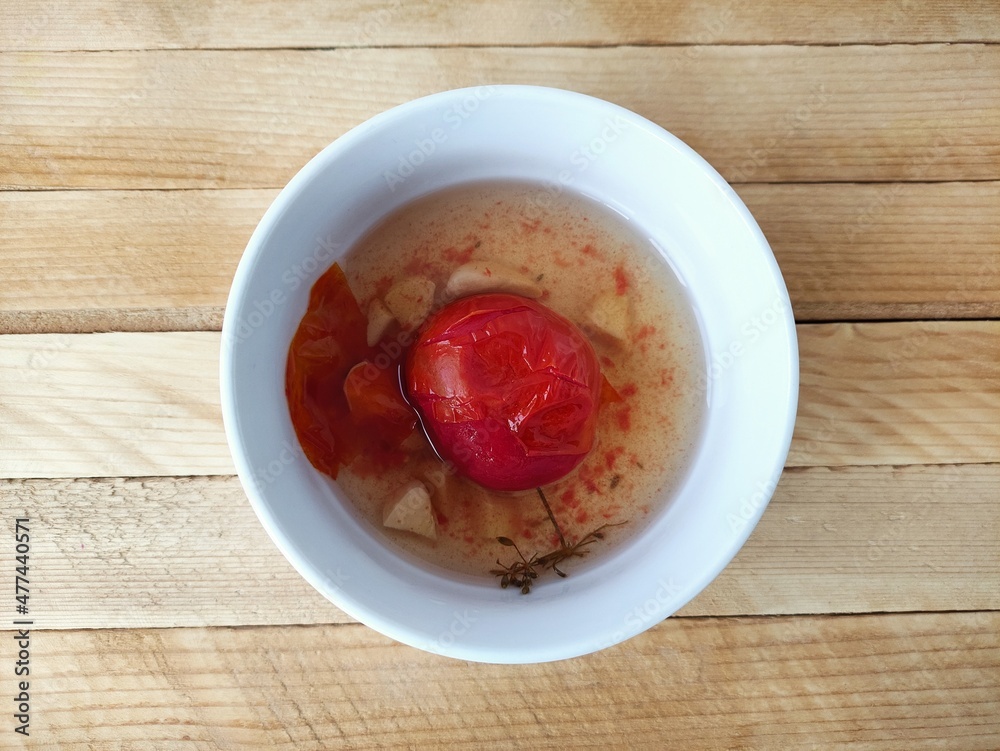 Pickled tomatoes with garlic in a plate on a wooden background Pickled tomatoes with garlic in a plate on a wooden background