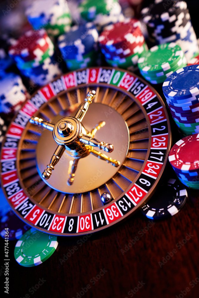 Casino theme. Roulette wheel and poker chips on colorful bokeh background. Casino theme. Roulette wheel and poker chips on colorful bokeh background.