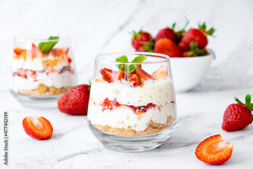 Photos Italian strawberry tiramisu dessert with mascarpone and whipped cream, savoyardi crumb and fresh strawberry in glass on marble