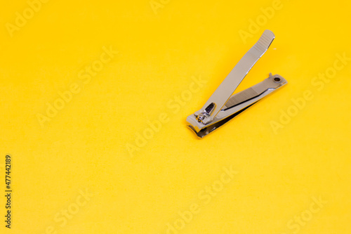 An Open Grey Nail Clipper in The Corner of Yellow Background